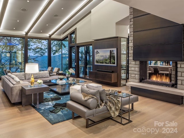 living room with plenty of natural light, light hardwood / wood-style flooring, a wall of windows, and a fireplace