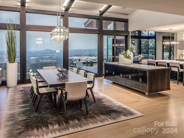 dining space featuring a wall of windows, hardwood / wood-style floors, an inviting chandelier, and a towering ceiling