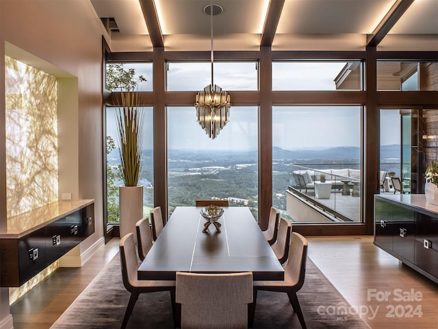 dining room with floor to ceiling windows, an inviting chandelier, a water and mountain view, and wood-type flooring