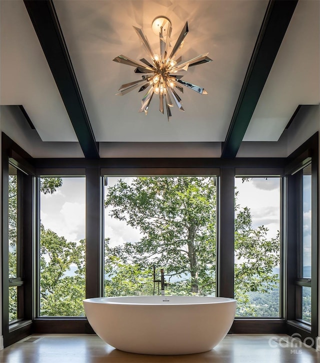 interior details with wood-type flooring, a bathing tub, and a chandelier