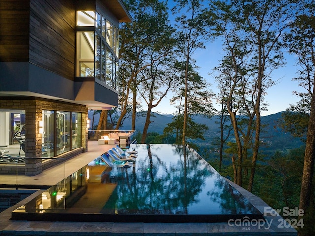 pool at dusk featuring a mountain view and a patio area