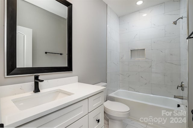 full bathroom featuring tiled shower / bath, vanity, and toilet