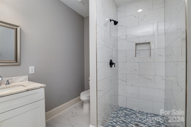 bathroom with vanity, toilet, and a tile shower