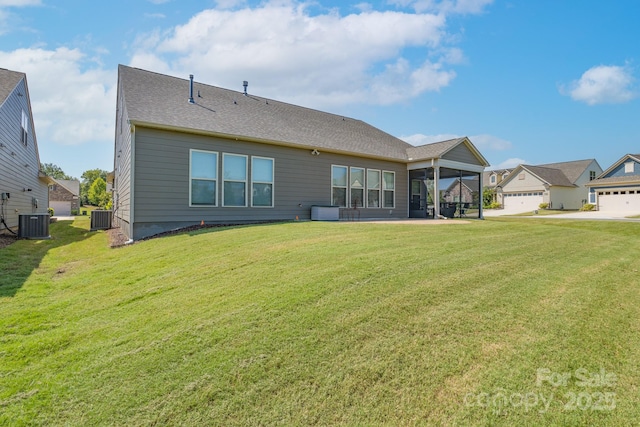 rear view of property featuring central air condition unit, a sunroom, and a yard