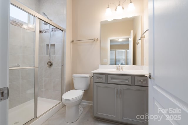 bathroom featuring tile patterned floors, vanity, toilet, and a shower with door