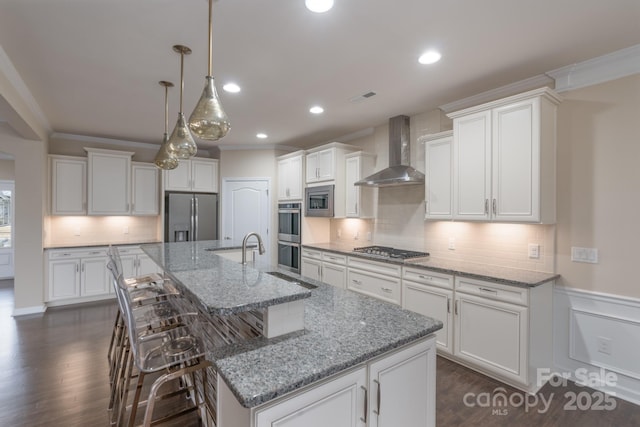 kitchen featuring white cabinets, appliances with stainless steel finishes, wall chimney exhaust hood, and a large island