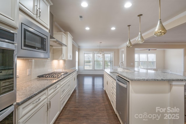 kitchen with white cabinets, appliances with stainless steel finishes, decorative light fixtures, and a spacious island