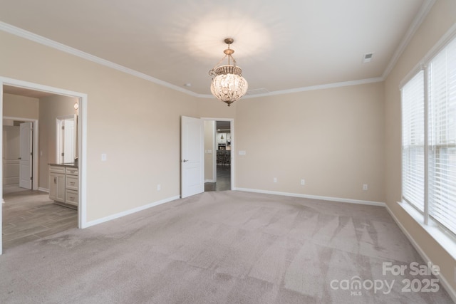 carpeted spare room featuring a notable chandelier and ornamental molding