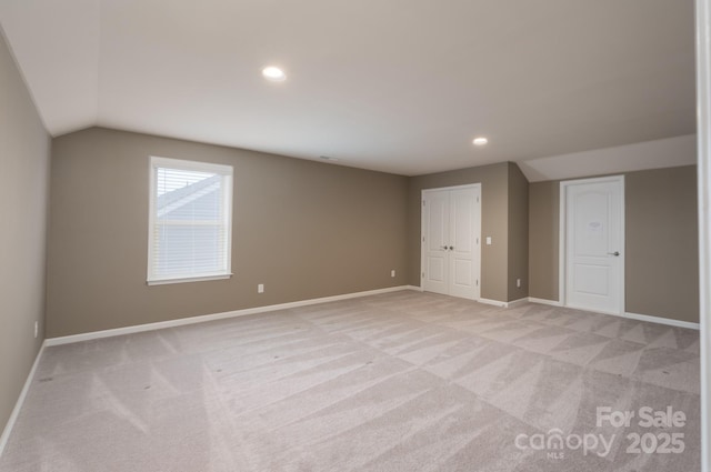 additional living space featuring light carpet and vaulted ceiling