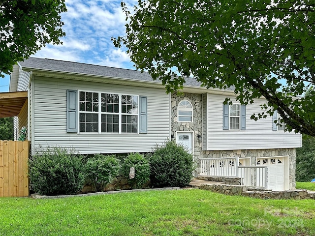 raised ranch featuring a front lawn and a garage