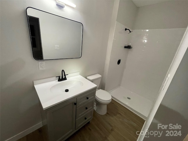 bathroom featuring toilet, vanity, wood-type flooring, and walk in shower