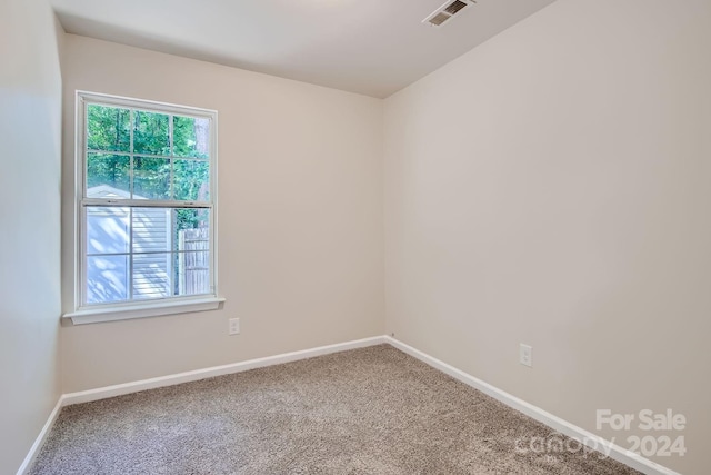 spare room with carpet floors, visible vents, and baseboards