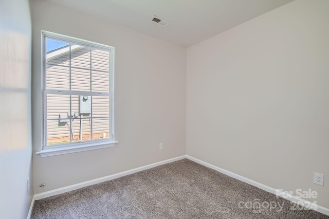 empty room featuring carpet flooring, visible vents, and baseboards