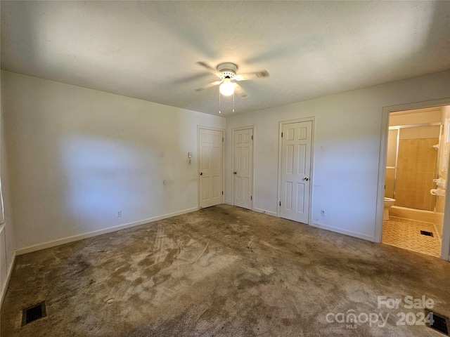 unfurnished bedroom featuring multiple closets, ensuite bathroom, ceiling fan, and carpet flooring