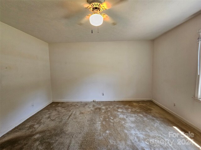 spare room with a textured ceiling, carpet, and ceiling fan