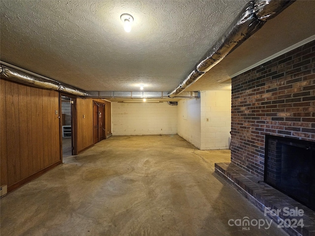 basement with wooden walls, a fireplace, brick wall, and a textured ceiling