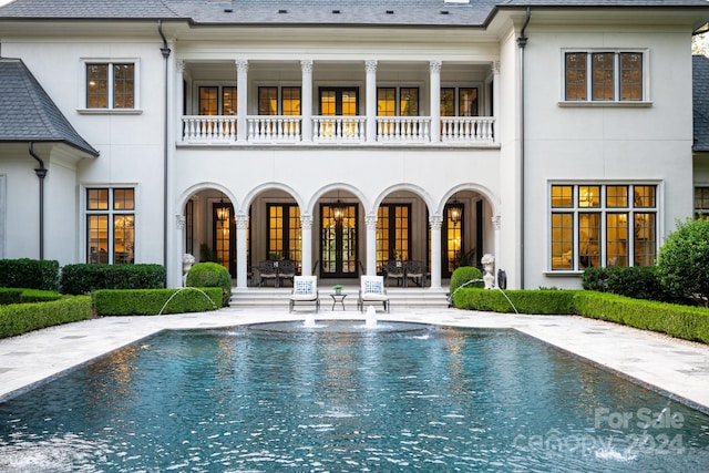 rear view of house featuring stucco siding, french doors, and a balcony