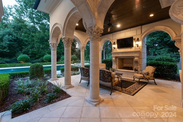 view of patio / terrace with an outdoor living space with a fireplace and ceiling fan