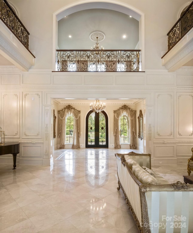 bedroom with french doors, a high ceiling, a chandelier, and a decorative wall