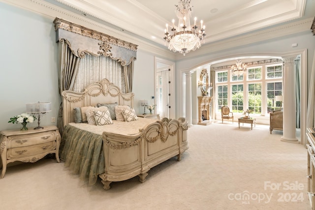 bedroom featuring crown molding, a chandelier, decorative columns, a tray ceiling, and light colored carpet