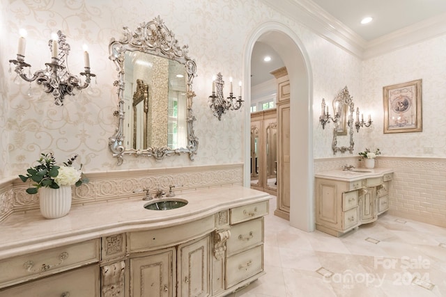 bathroom with wainscoting, wallpapered walls, crown molding, and a sink