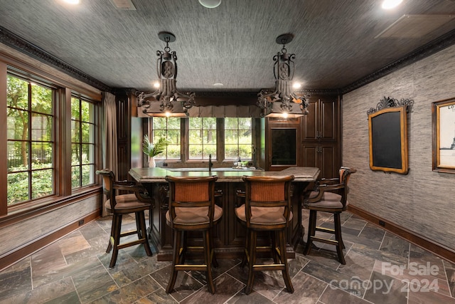 bar featuring decorative light fixtures, baseboards, and stone tile flooring