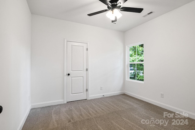 spare room with carpet floors, visible vents, baseboards, and a ceiling fan