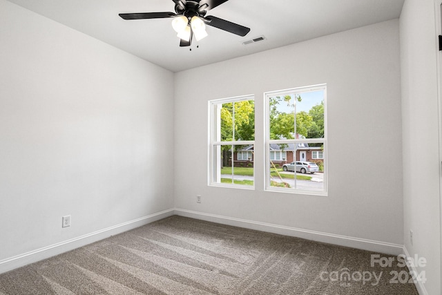 empty room featuring carpet floors, visible vents, ceiling fan, and baseboards