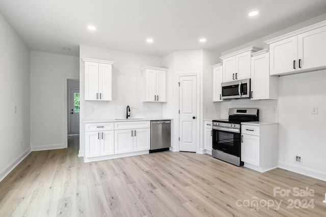 kitchen featuring stainless steel appliances, tasteful backsplash, a sink, and white cabinets