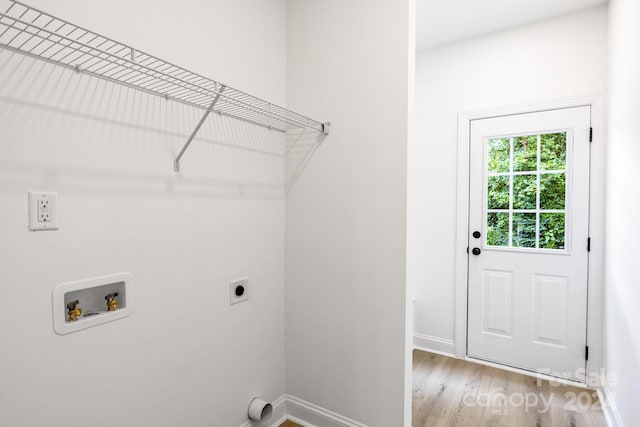 clothes washing area with hookup for a washing machine, light wood-style flooring, hookup for an electric dryer, laundry area, and baseboards