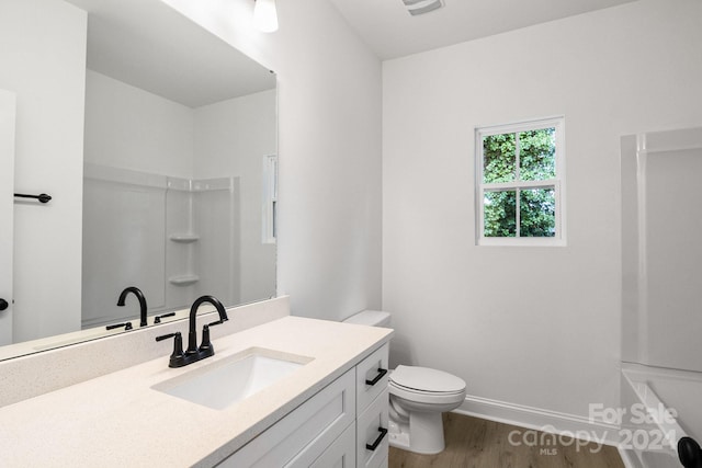 full bathroom with toilet, vanity, wood finished floors, baseboards, and walk in shower