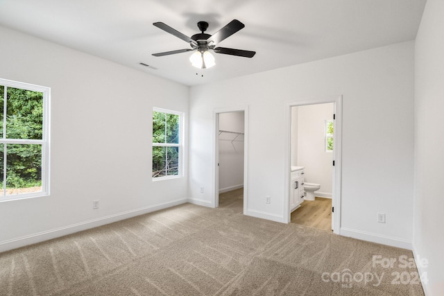 unfurnished bedroom with light carpet, a spacious closet, visible vents, and baseboards