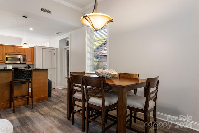 dining space featuring ornamental molding and dark wood-type flooring