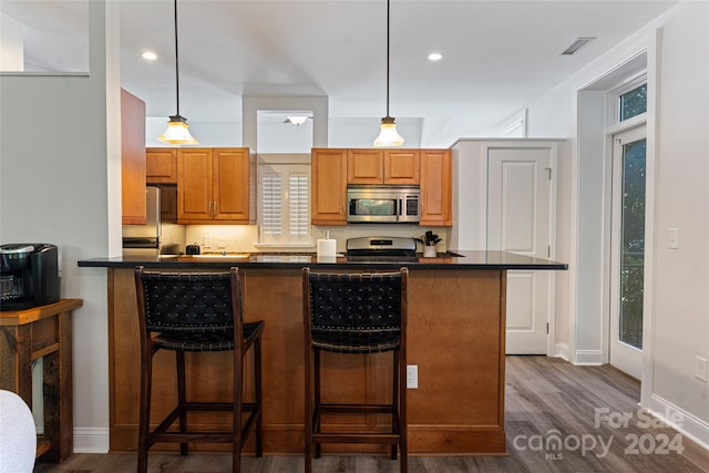 kitchen featuring pendant lighting, a kitchen bar, stainless steel appliances, and dark hardwood / wood-style floors