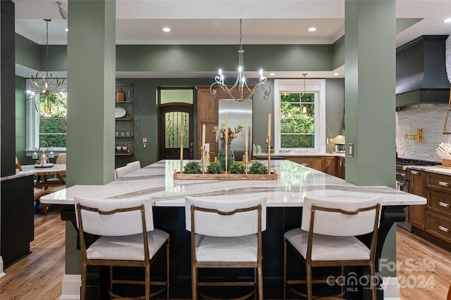 kitchen with wood-type flooring, premium range hood, high quality appliances, crown molding, and a chandelier