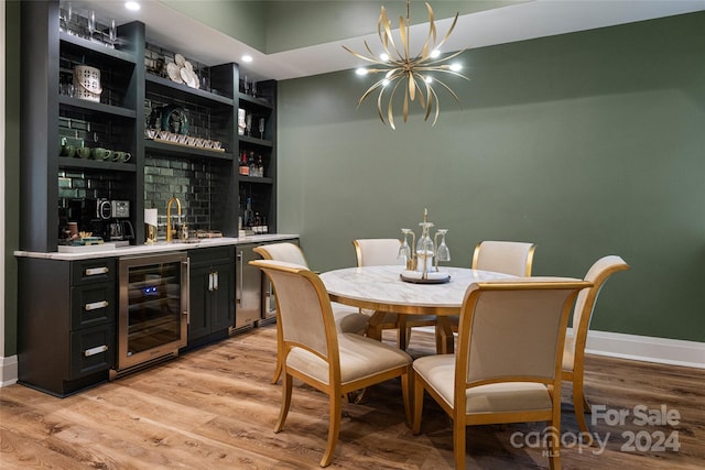 dining space featuring indoor wet bar, beverage cooler, light hardwood / wood-style flooring, and a notable chandelier