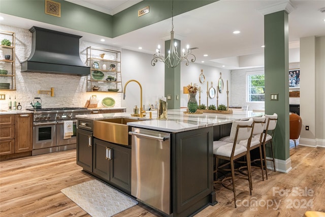 kitchen with a kitchen island with sink, light wood-type flooring, stainless steel appliances, and custom exhaust hood