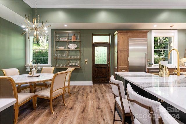 dining area featuring a wealth of natural light, ornamental molding, a chandelier, and light hardwood / wood-style floors