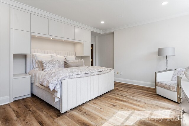 bedroom with light wood-type flooring and ornamental molding