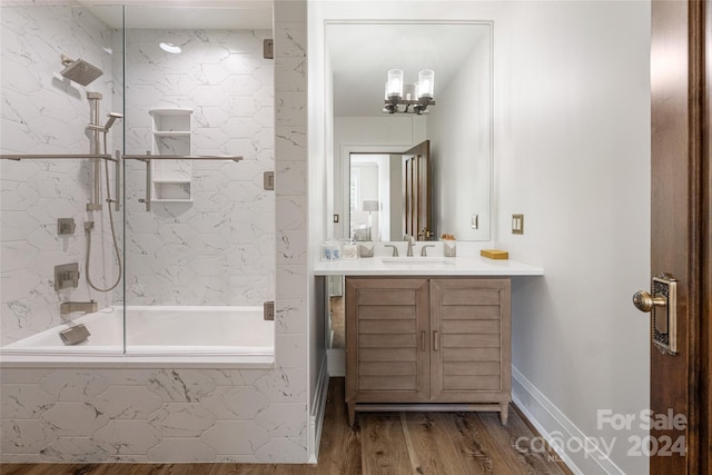 bathroom featuring wood-type flooring, tiled shower / bath combo, and vanity