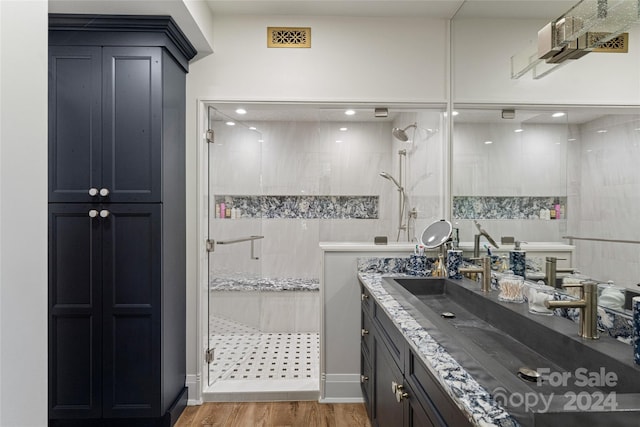 bathroom with vanity, a tile shower, and wood-type flooring