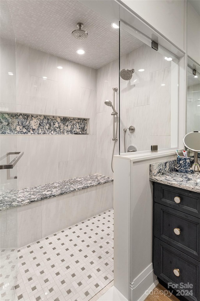 bathroom with vanity, a tile shower, and tile patterned flooring