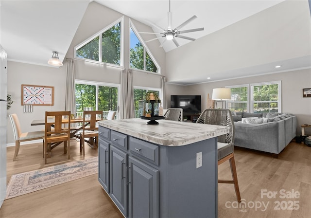 kitchen featuring ceiling fan, high vaulted ceiling, light hardwood / wood-style flooring, a center island, and gray cabinets