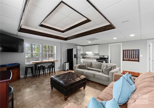 living room with a raised ceiling and sink