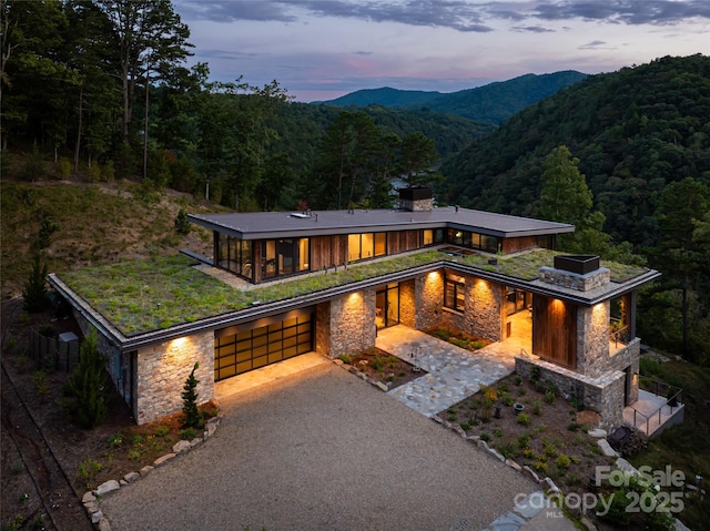 view of front of house with a mountain view, a garage, an outdoor fireplace, and a patio