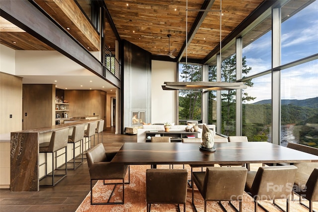 dining space featuring a mountain view, wooden ceiling, expansive windows, and a towering ceiling