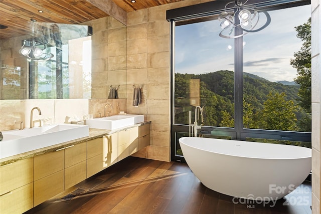 bathroom featuring hardwood / wood-style floors, wood ceiling, vanity, tile walls, and a bathing tub