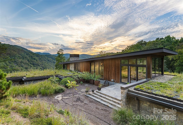 property exterior at dusk with a mountain view and a patio