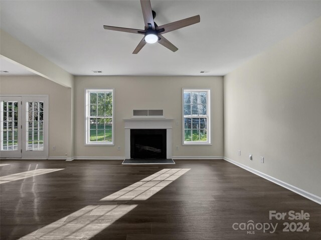 unfurnished living room with ceiling fan, dark hardwood / wood-style floors, and plenty of natural light