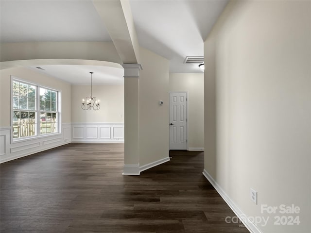 unfurnished dining area with visible vents, dark wood-type flooring, ornate columns, a decorative wall, and a notable chandelier